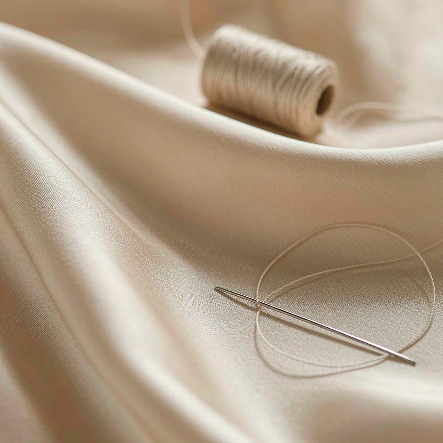 Hand stitching on ivory silk with a single threaded needle
