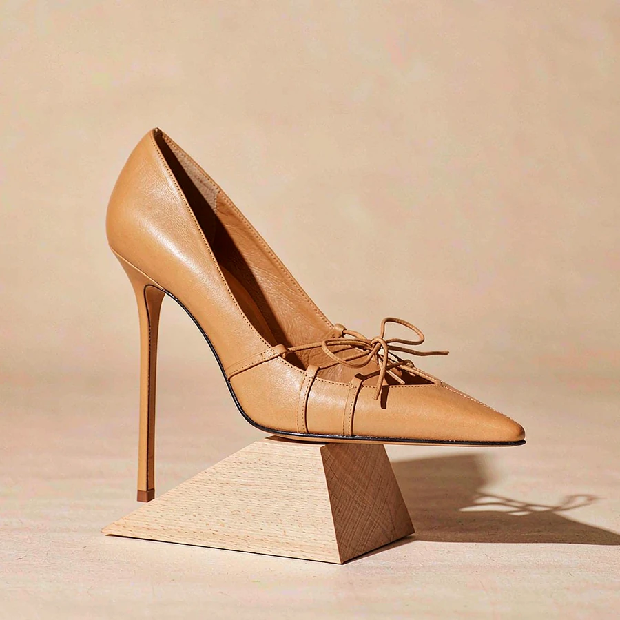 Tan leather pump presented on a pale oak block