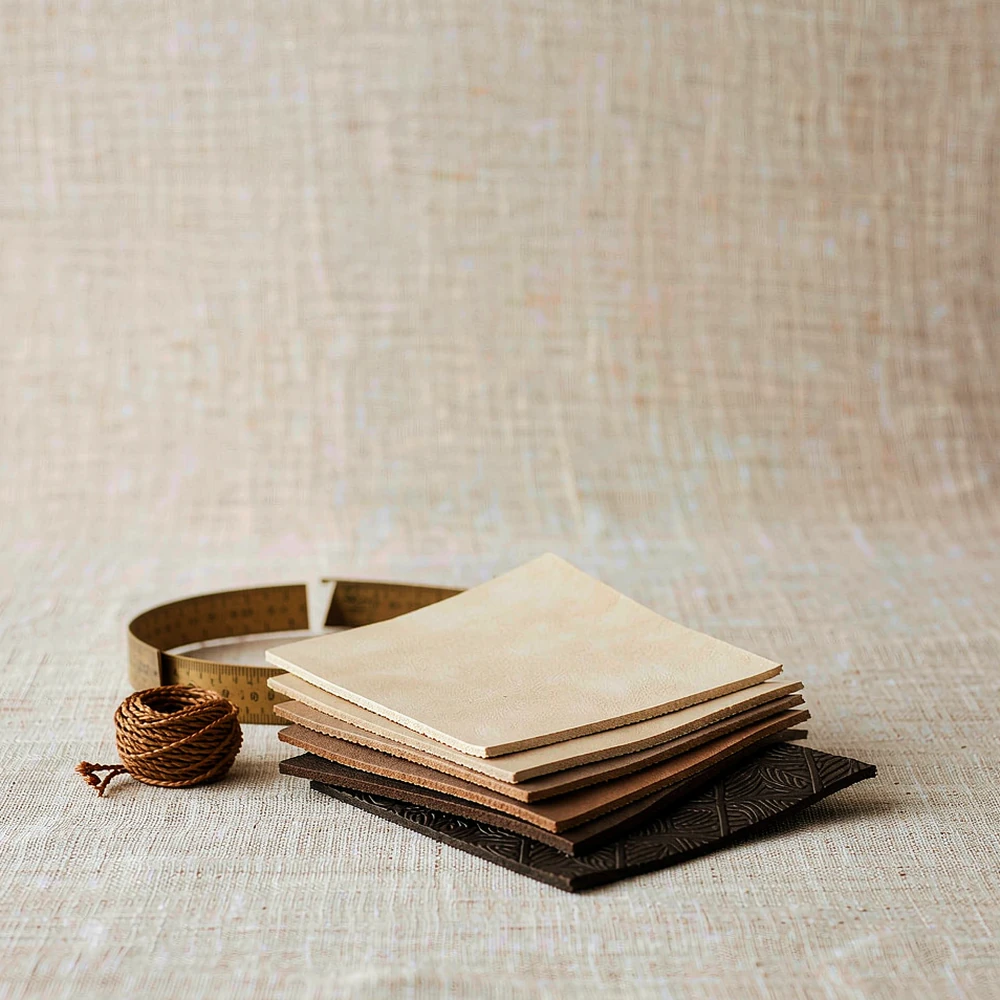 Leather swatches, waxed thread and a brass ruler on natural linen